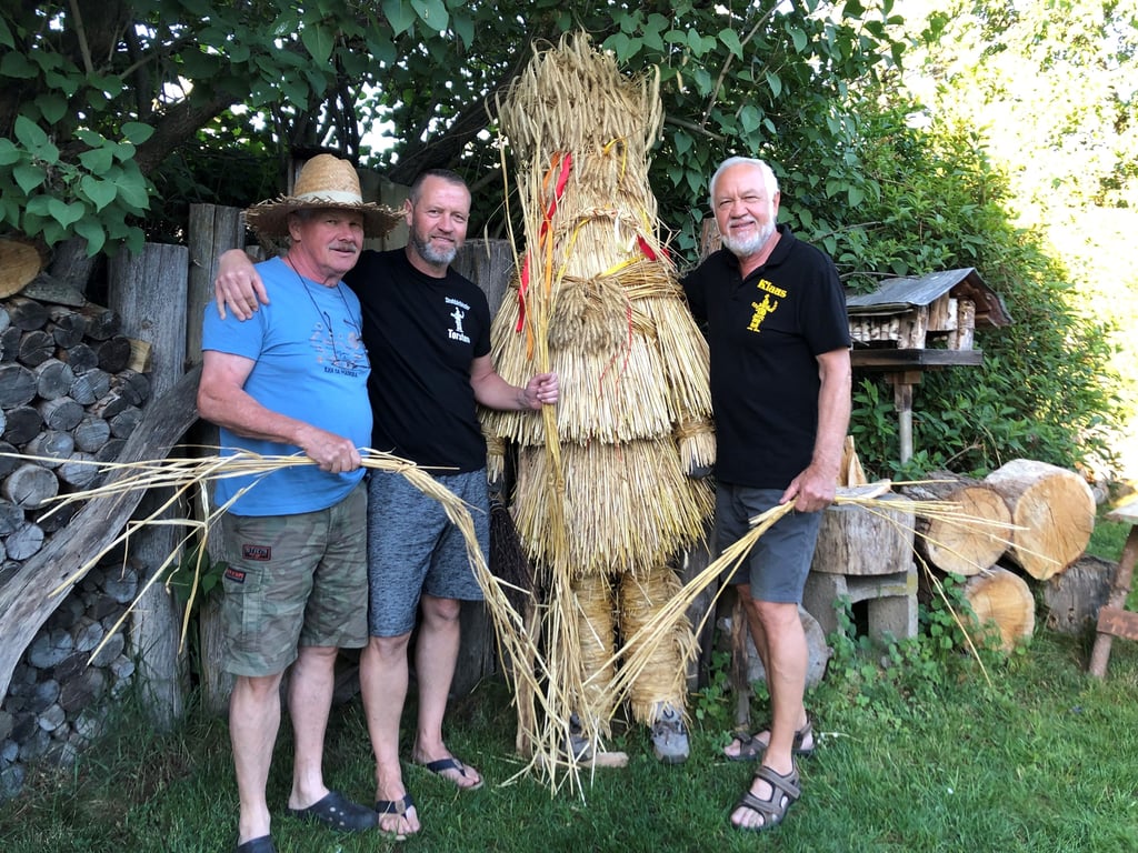 Bernhard Müller (l.) hat die Technik des Strohbärenbindens in den 80er Jahren gelernt. Inzwischen hat er seinen Neffen Torsten Müller (M.) angelernt. Dessen Vater Klaus Müller (r.) hilft mit anderen Vereinsmitgliedern bei der aufwändigen Prozedur mit.