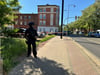Eine bewaffnete und vermummte Polizistin steht am Montag (13. Mai 2024) in Magdeburg-Fermersleben nahe dem Tatort, wo eine 51-jährige Frau von einem Mann niedergeschossen worden war.