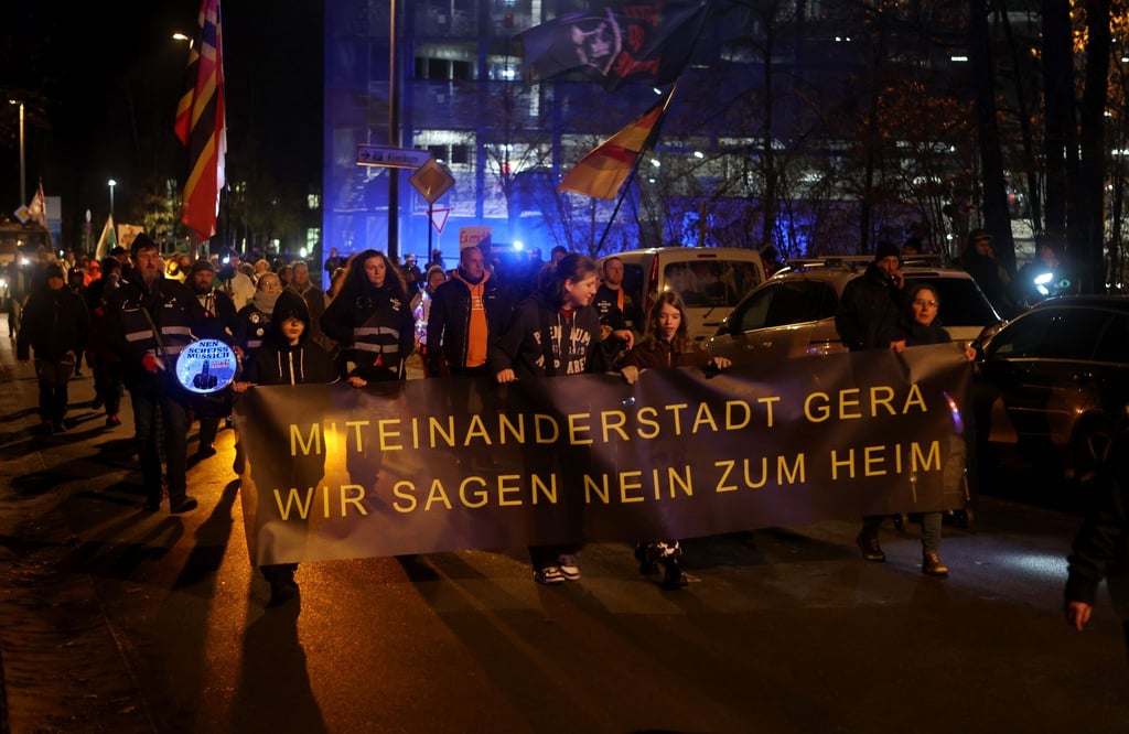 Teilnehmer einer Demonstration gegen eine geplante Erstaufnahmeeinrichtung für Flüchtlinge im ehemaligen Wismut Krankenhaus laufen zu dem Krankenhausgelände.