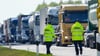 Polizeibeamte stehen kurz vor der Abfahrt zum Parkplatz Rosskower Heide an der Autobahn A24 und winken Lastwagen aus dem fließenden Verkehr, die an einer Kontrollstelle den Abstand zum vorausfahrenden Fahrzeug unterschritten hatten.