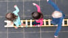 Kinder balancieren während eines Pressetermins auf dem Spielplatz einer Kindertagesstätte auf einem Brett.