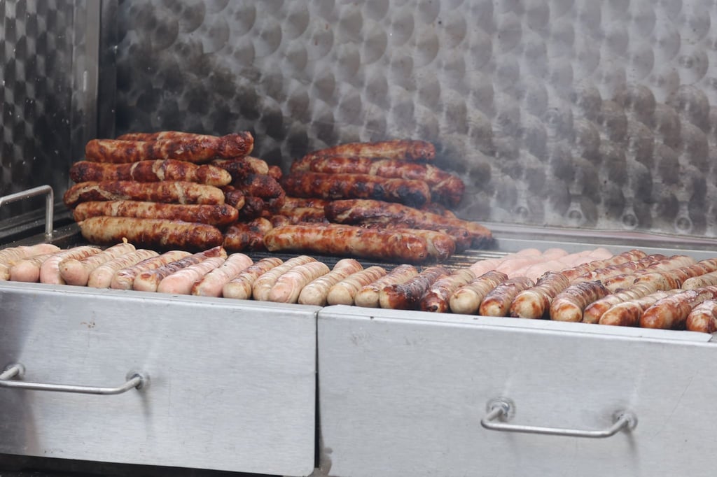 Bratwürste liegen auf einem Holzkohlegrill.