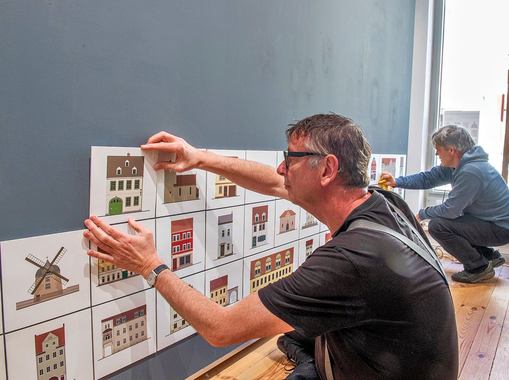 Für seine mehrteilige und -jährige Schau „1.000 Naumburger Fassaden“ klebt Ad van der Kouwe in der Kunsthalle im Steinweg wie ein Fliesenleger seine Grafiken an die Wand – unterstützt von Ralph Hälbig (r.).