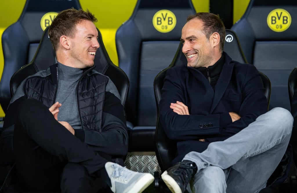Leipzigs Trainer Julian Nagelsmann (l) und Oliver Mintzlaff, Geschäftsführer RB Leipzig sitzen vor dem Spiel auf der Trainerbank und unterhalten sich. Mintzlaff trauert dem Abgang von Nagelsmann hinterher.