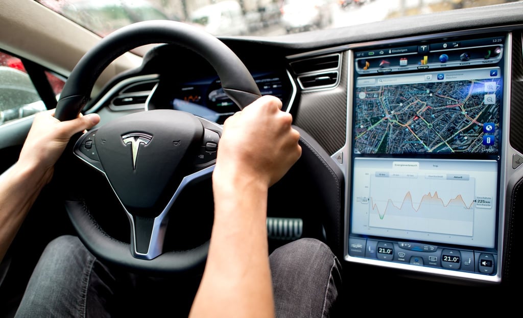 Ein Mann sitzt in einem Tesla Model S am Lenkrad: Elon Musk sagt, er sei mit seinen Versprechen zu selbstfahrenden Autos oft zu optimistisch gewesen.