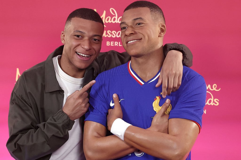 Frankreichs Fußballstar Kylian Mbappé steht neben seinem Wachsabbild.
