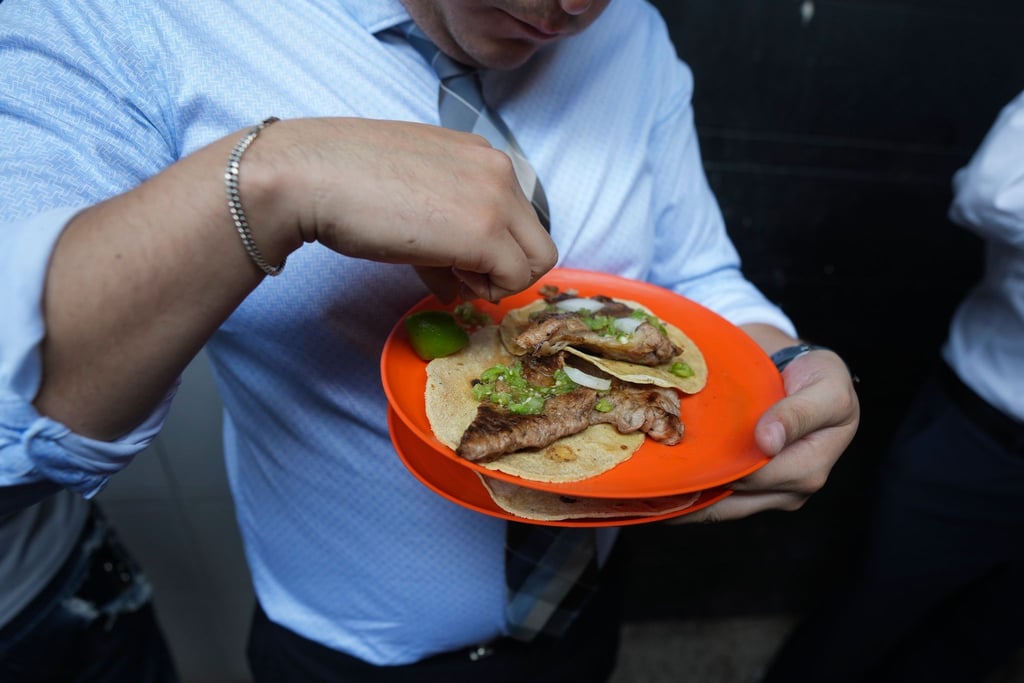 Ein Kunde drückt Limettensaft auf seine Tacos.