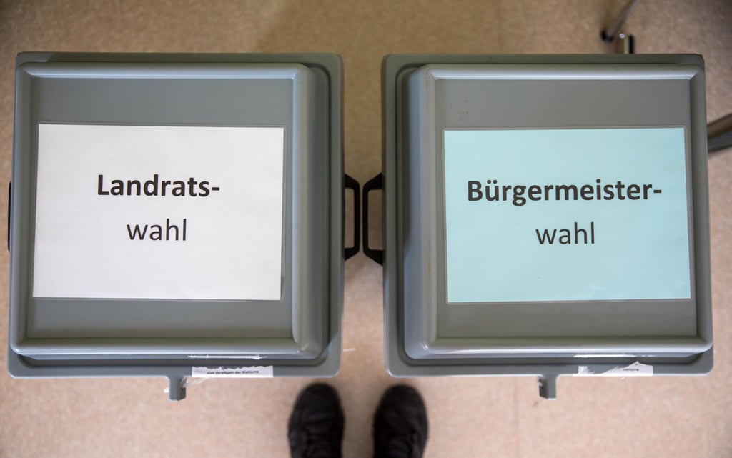 Zettel mit der Aufschrift „Landratswahl“ und „Bürgermeisterwahl“ liegen auf den Wahlurnen im Wahllokal.