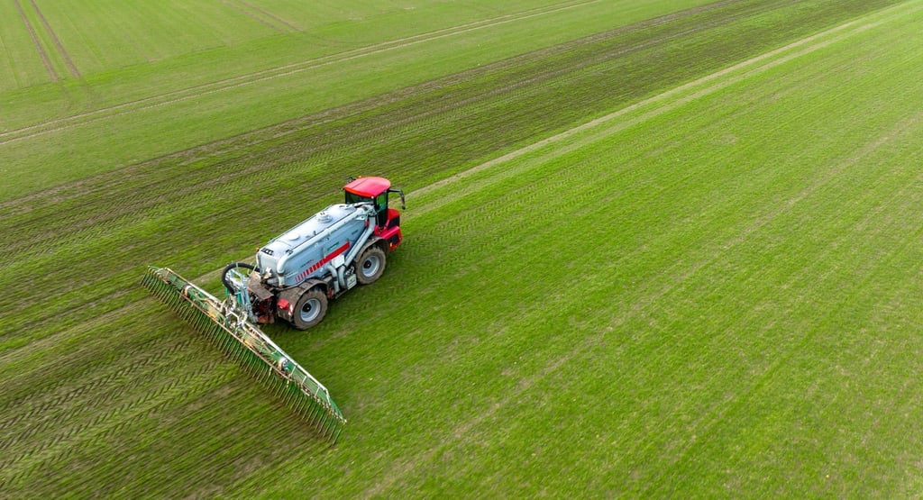 Ein Landwirt bringt mit seinem Gespann Gülle im sogenannten Schleppschuh Verfahren auf einem Feld aus.