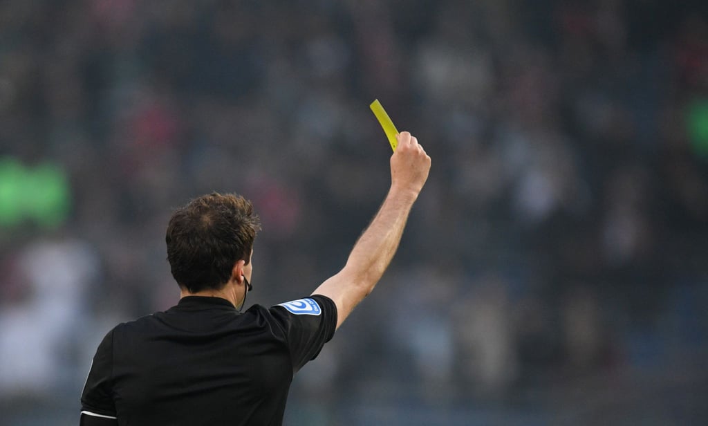 Ein schiedsrichter zeigt einem Spieler die Gelbe Karte.