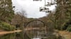 Die Rakotzbrücke aus Basaltsteinen im Kromlauer Rhododendronpark spiegelt sich bei bedecktem Wetter im Rakotzsee.