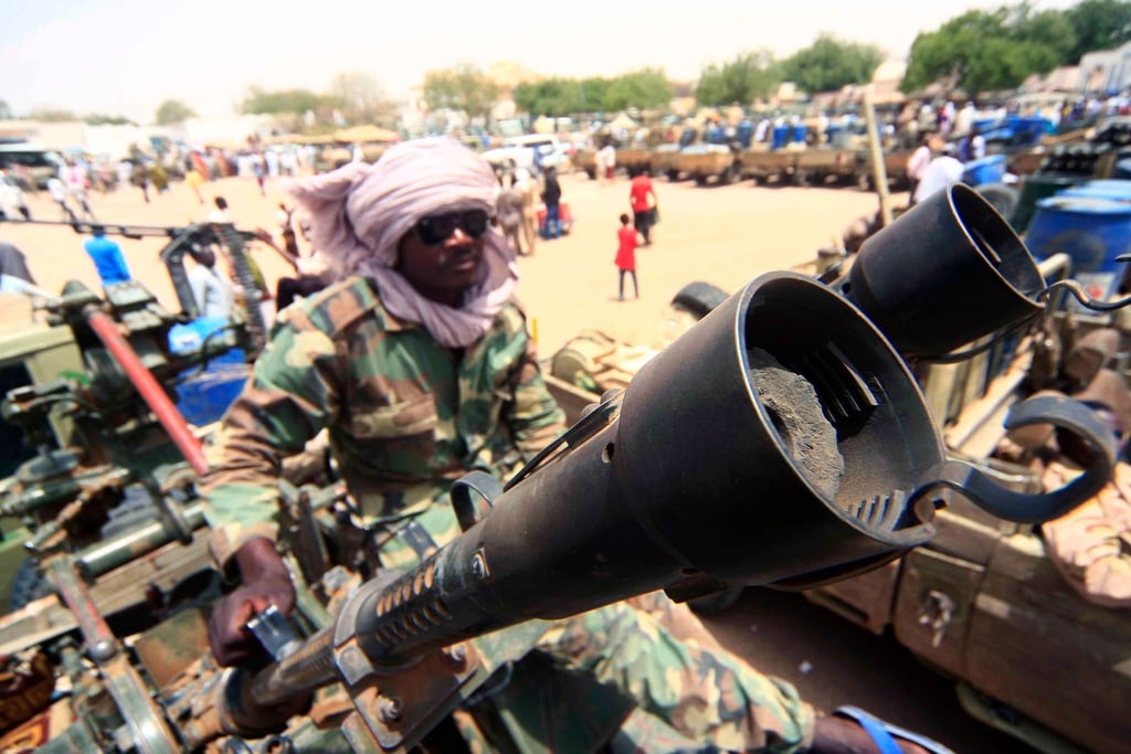Ein Milizionär sitzt neben militärischer Ausrüstung, die angeblich während eines Gefechts im umkämpften Gebiet in Süd-Darfur erbeutet wurde.