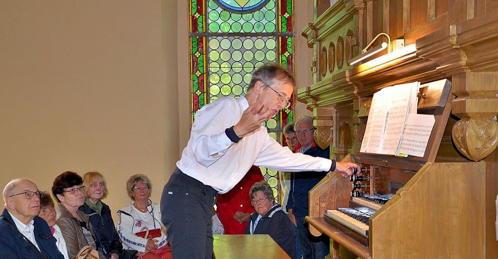 Wieland Meinhold erklärt in Rathmannsdorf interessierten Zuhörern vor Beginn des Wandelkonzerts, wie eine Orgel funktioniert.