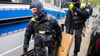 Polizisten tragen bei einer Hausdurchsuchung in Berlin-Kreuzberg einen Karton zu einem Fahrzeug.
