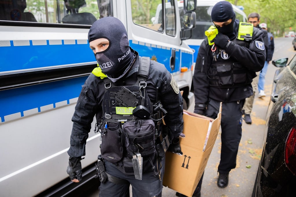 Polizisten tragen bei einer Hausdurchsuchung in Berlin-Kreuzberg einen Karton zu einem Fahrzeug.
