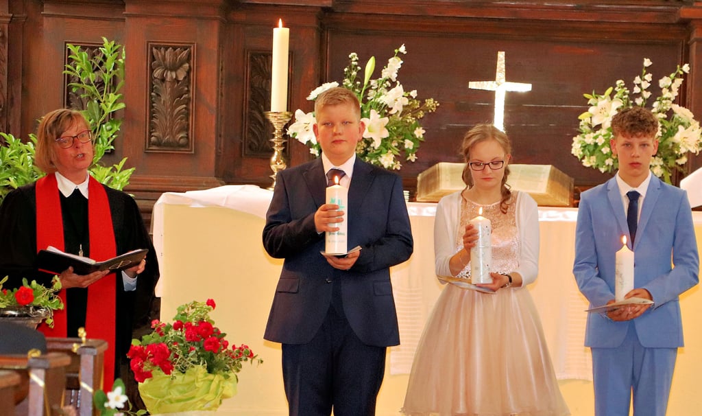 Die Konfirmierten Thaddäus Schlag, Elisa Bosse und Nelias Brien (v. li.) mit den Konfirmationskerzen in der Hand. Links Superintendentin Ute Mertens.