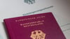 Eine Einbürgerungsurkunde der Bundesrepublik Deutschland und ein deutscher Reisepass liegen auf einem Tisch.
