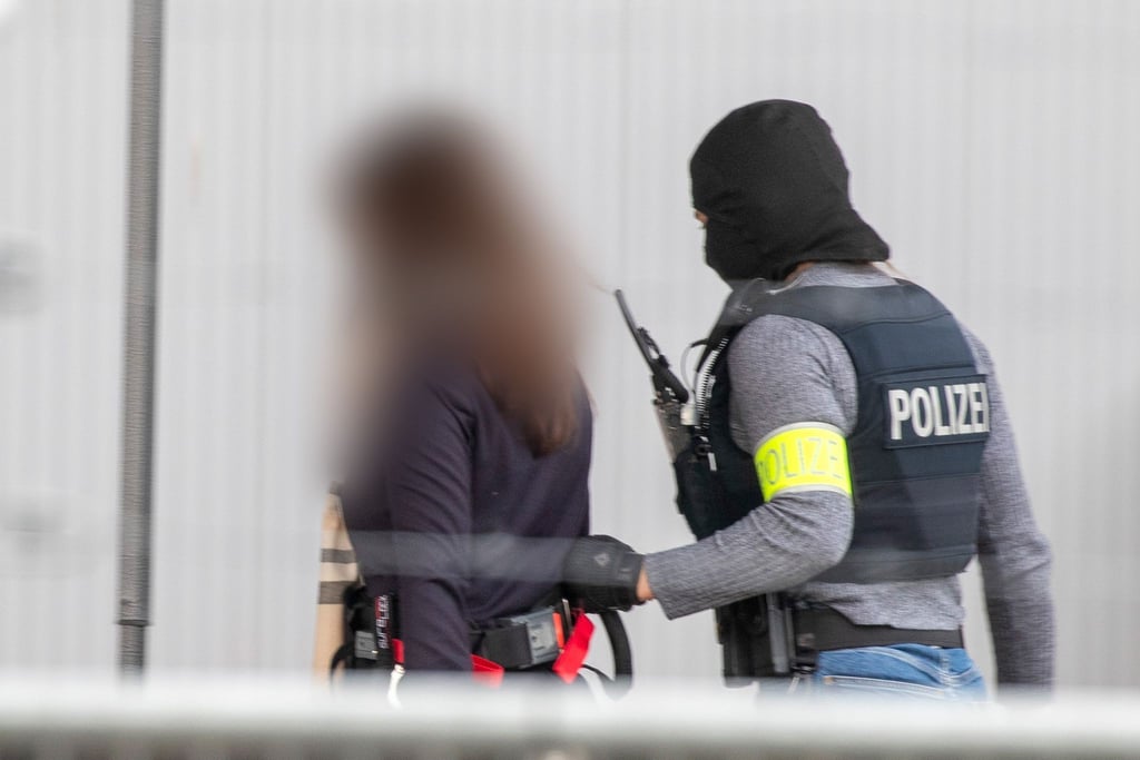 Polizei-Spezialeinsatzkräfte führen eine Angeklagte in das provisorische Gerichtsgebäude.