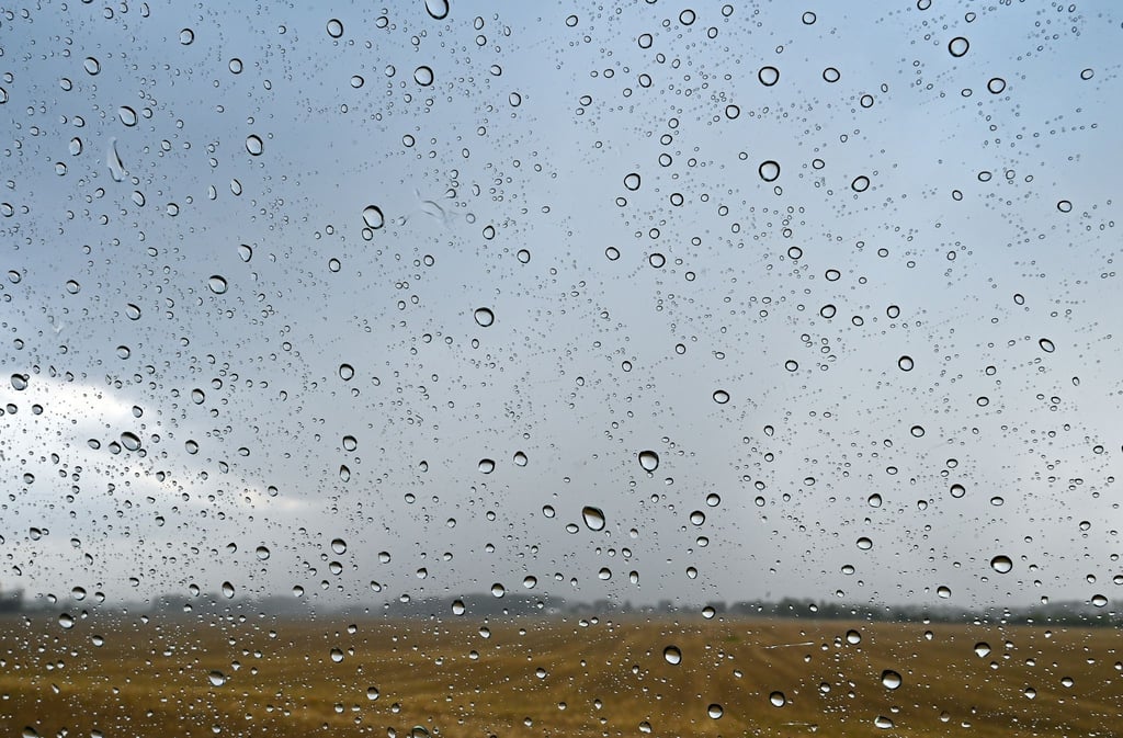 Regentropfen sind an einer Autoscheibe vor der Landschaft im Osten von Brandenburg zu sehen.