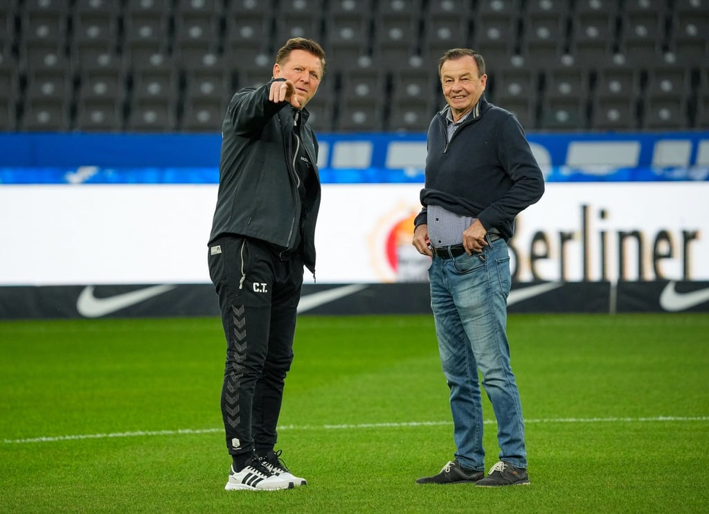 Magdeburgs Chef-Trainer Christian Titz (l) und sein Sportdirektor Otmar Schork (r) unterhalten sich vor dem Spiel.
