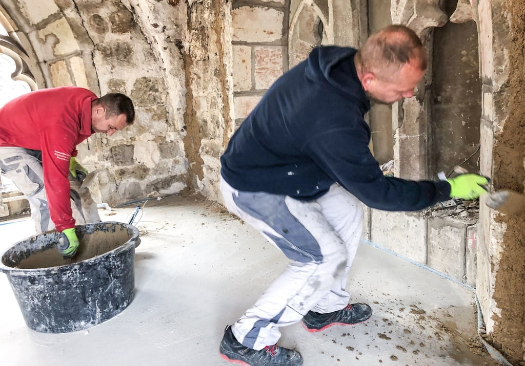 Mitarbeiter der Immobilien-Service Wiedenbein GmbH bringen einen Kalkputz auf die Wände der Kapelle auf.