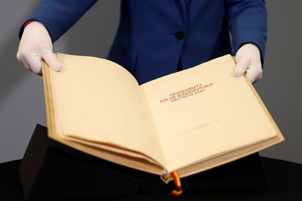Eine Mitarbeiterin des Parlamentsarchivs des Deutschen Bundestages zeigt Seiten des Originalbuchs des Grundgesetzes, der Verfassung der Bundesrepublik Deutschland, während einer Pressepräsentation im Vorfeld des 75-jährigen Bestehens der Verfassung.