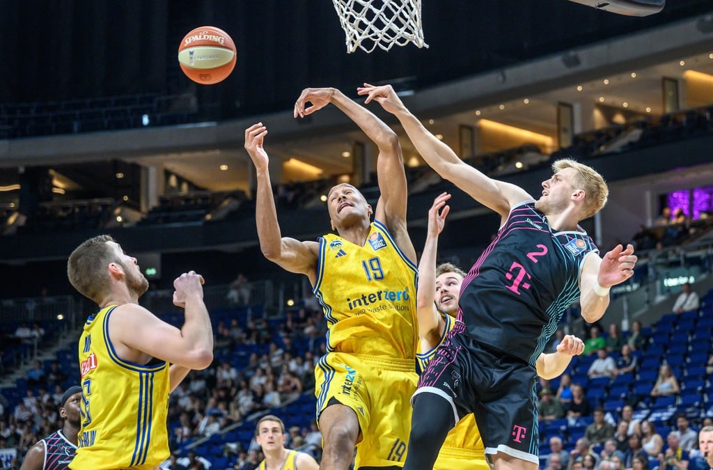 Berlins Louis Olinde (M) springt zum Korb gegen Sam Griesel (r) von den Telekom Baskets Bonn.