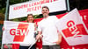 Sven und Bianca, beide Lehrer an einer Neuköllner Schule, stehen mit zwei GEW-Flaggen beim Warnstreiks an den Berliner Schulen in Berlin-Kreuzberg vor einem Banner mit der Aufschrift "Kleinere Lerngruppen jetzt!".