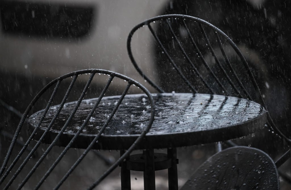Hagel und Regen prasseln auf einen Tisch vor einem Café.