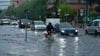 Ein Radfahrer und Autos fahren im Schritttempo durch die überflutete Zeppelinstraße.