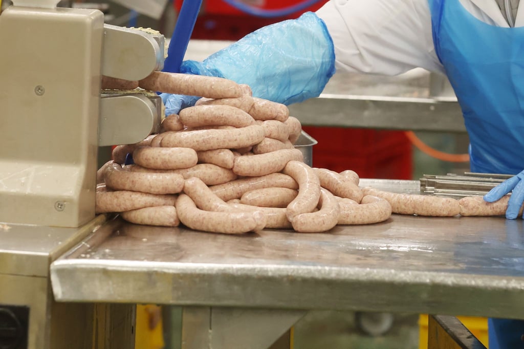 Ein Mitarbeiter arbeitet in der Produktion von Wurstwaren in der Wolf Wurstfabrik.