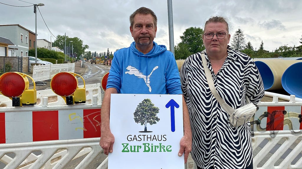 Gastronom Olaf Kellner steht mit Anwohnerin Simone Mann vor der Baustelle am Burgstaller Weg in Magdeburg. Kellner ließ für seine Gaststätte Schilder anfertigen.
