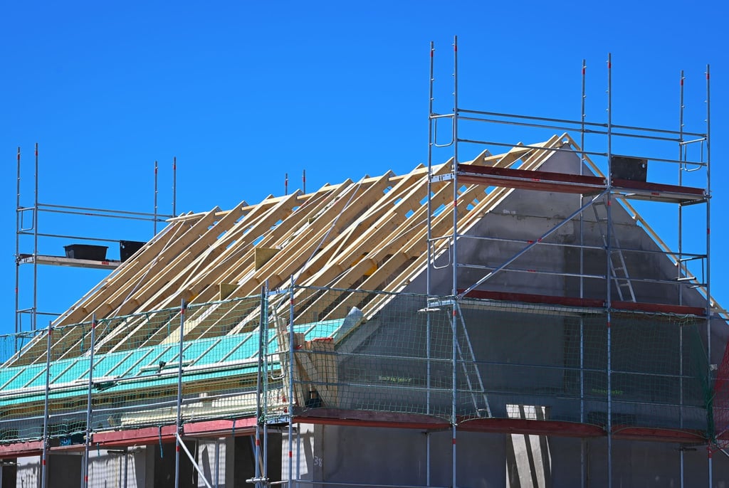 Ein Baugerüst steht an der Fassade eines im Bau befindlichen Einfamilienhauses.