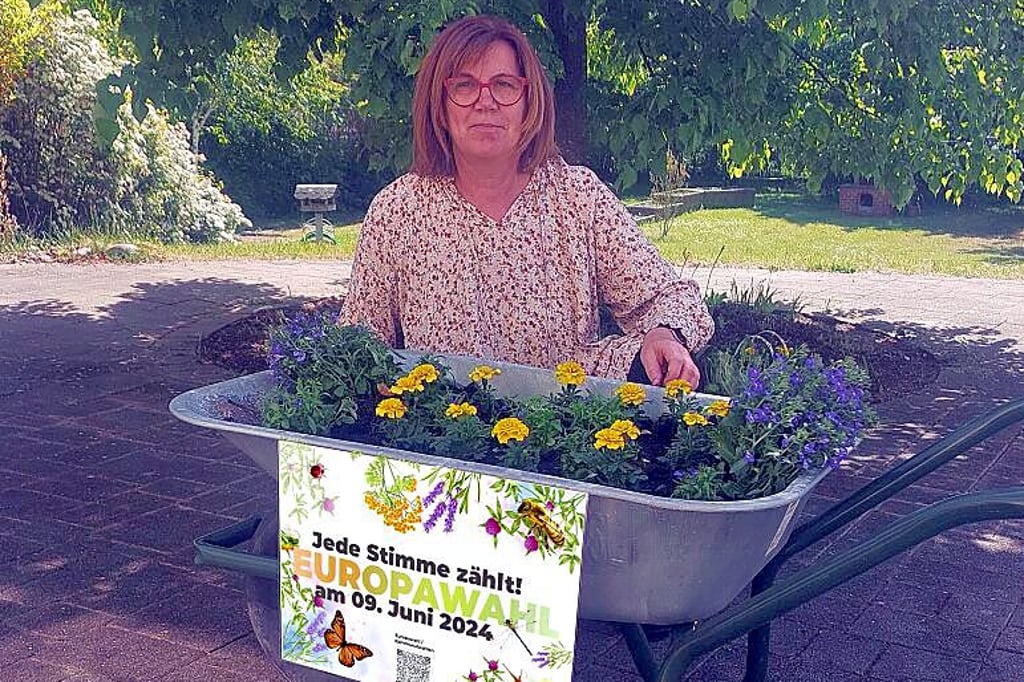 Die Europabeauftragte Bianca Laukat präsentiert stolz die mit Blumen geschmückte Schubkarre.