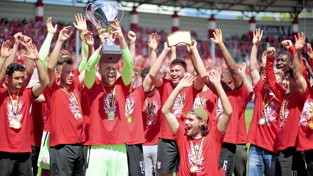 Torwart Sven Müller, der den HFC vor dem K.o. rettete, hat den Pokal vom sitzenden Jonas Nietfeld (mit Mütze) erhalten und reckt ihn in die Höhe.