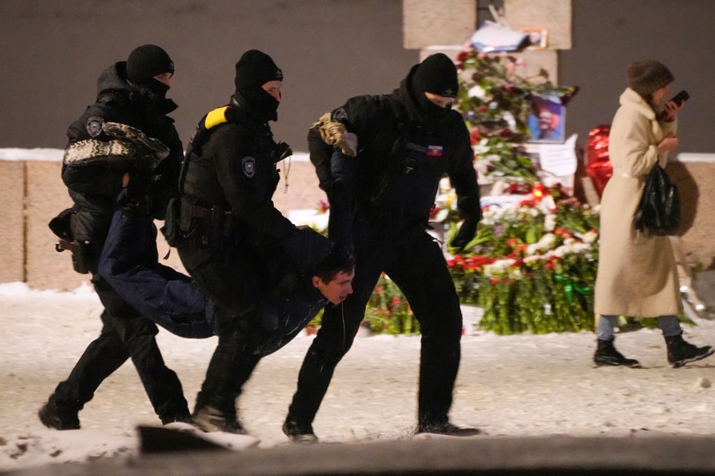 Polizeibeamte halten einen Mann fest, der Blumen zu Ehren von Alexej Nawalny an einem Denkmal für die Opfer der sowjetischen Unterdrückung in St. Petersburg niedergelegt hat.