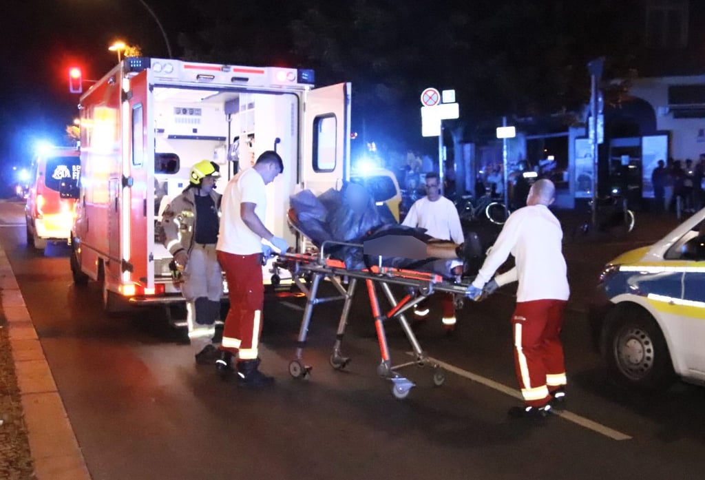 Rettungssanitäter bringen einen Verletzten zu einem Rettungswagen.