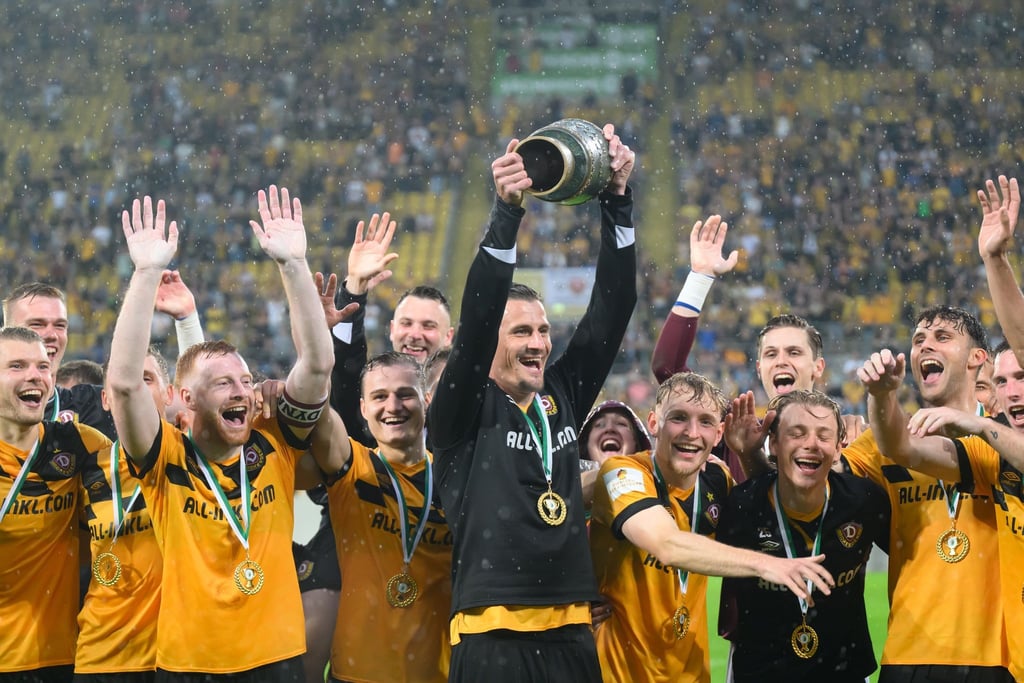 Dynamos Stefan Kutschke und die Mannschaft jubeln mit dem Pokal nach dem Sieg.