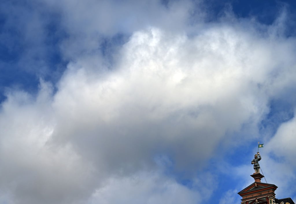 Wolken ziehen über die Statue auf dem Haus zum breiten Herd am Fischmarkt.