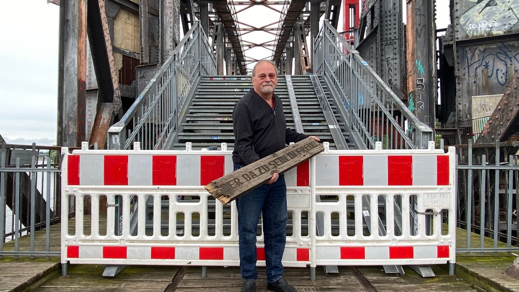 Rolf Onnen, der Eigentümer der Hubbrücke, hält die zerstörte Holzbohle in der Hand, wegen der die Brücke gesperrt war. Als diese Aufnahme entstand, war der Elbübergang noch abgeriegelt. Mittlerweile ist die Brücke für Fußgänger wieder geöffnet.