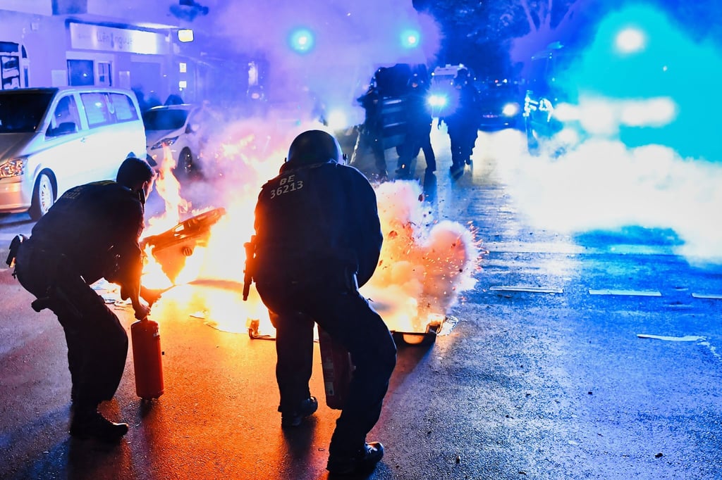 Polizeibeamte versuchen auf der Sonnenallee in Neukölln zwei in Brand gesetzte Mülltonnen zu löschen. In der Sonnenallee kam es zu teilweise gewalttätigen Auseinandersetzungen von Menschen, die „Freiheit für Palästina“ skandierten.