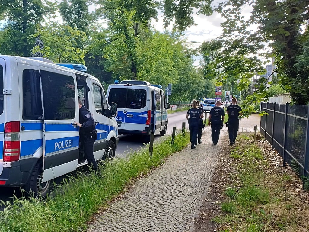 Polizisten gehen am abgesperrten Tatort in der Potsdamer Geschwister-Scholl-Straße entlang.