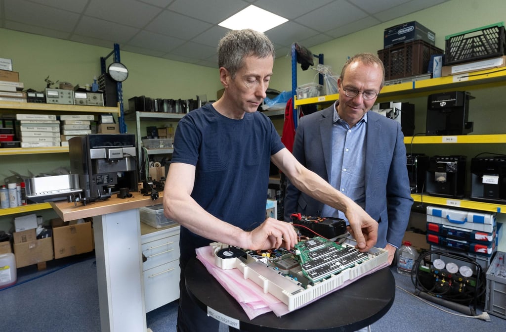 Wolfram Günther (Bündnis90/Die Grünen), Umweltminister von Sachsen, beobachtet Lothar Prohl, Servicetechniker, in der Werkstatt der HSC HomeElectronic Service Center GmbH in Leipzig bei der Reparatur eines Ceranfelds.