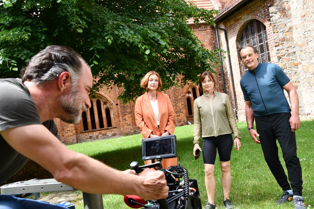 Kameramann Pascal Schmit hat die Aufnahmen für „Mit Herz und Holly“ auf dem Klosterhof am Dom in Havelberg im Kasten. Die Schauspieler Aglaia Szyszkowitz, Inka Friedrich und Joachim Raaf (von links) drehen für eine Radtour, die in der neuen Folge der ZDF-Serie zu sehen sein wird.