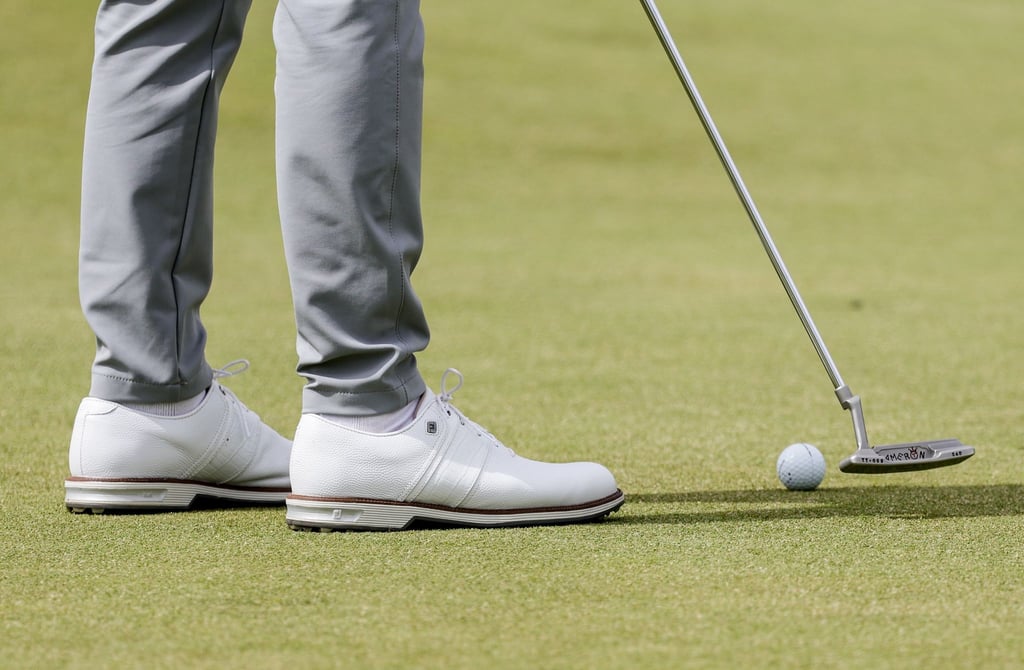 Ein Golfspieler puttet den Ball auf dem Grün.