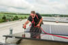 Ralf Veit von der Firma Würkner aus Farnstädt montiert auf dem Dach der Grundschule Laucha die Module der Solaranlage. 