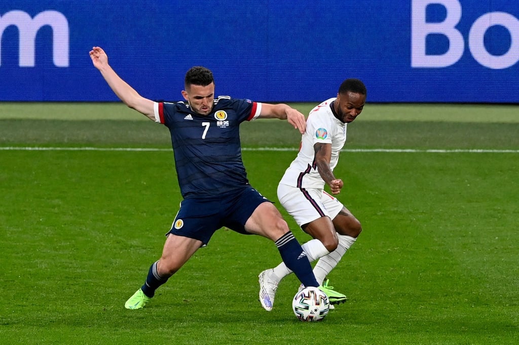 Der Schotte John McGinn (l) ist im Zweikampf vor Raheem Sterling am Ball.