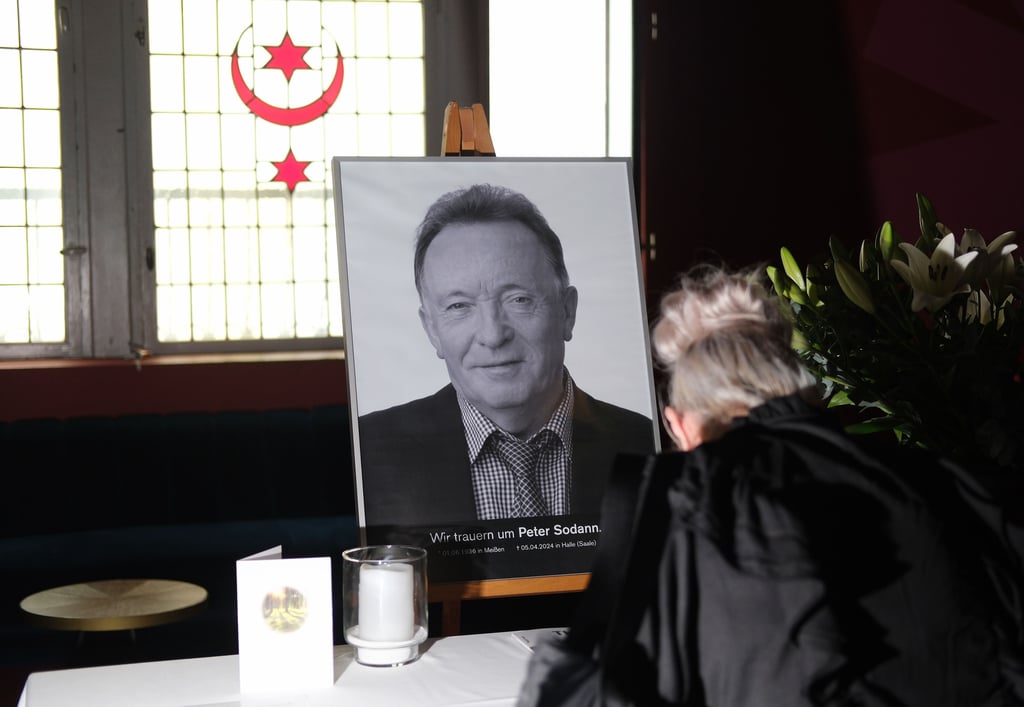 Teilnehmer einer Trauerfeier tragen sich vor einem Bild des Schauspielers Peter Sodann im Neuen Theater in Halle in ein Kondolenzbuch ein.