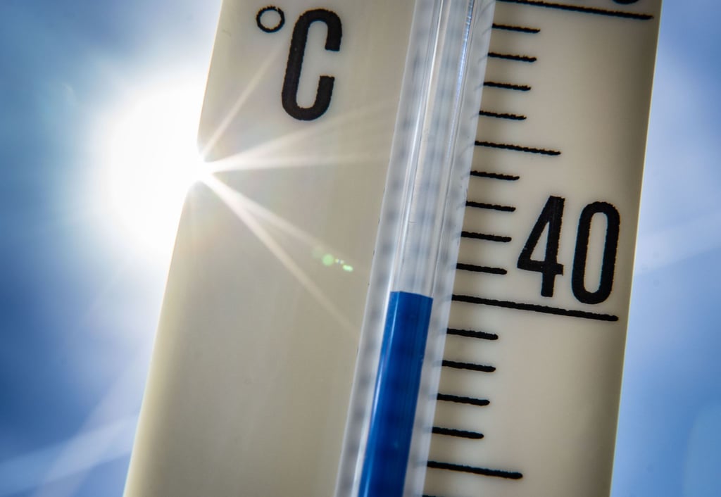 Ein Außenthermometer zeigt vor dem blauen Himmel und der Sonne eine Temperatur von nahezu 40 Grad Celsius an.