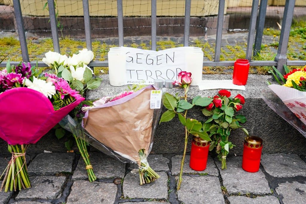 Kerzen, Blumen und ein Blatt Papier mit der Aufschrift „Gegen Terror“ stehen am Tatort auf dem Mannheimer Marktplatz.